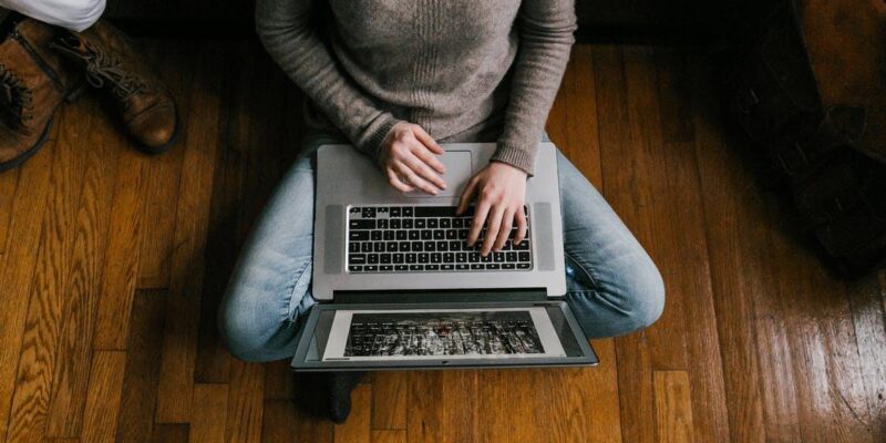 Person in Gray Long Sleeve Shirt Using Macbook Pro