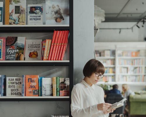 Boy in White Dress Shirt Standing Beside Books